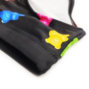 Detailed macro view of black swim fabric with colorful gummy bear prints and double stitching