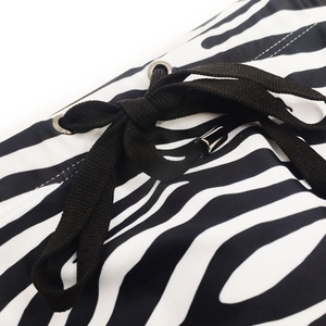 Detail of zebra print swim trunks featuring black braided drawstring and silver eyelets