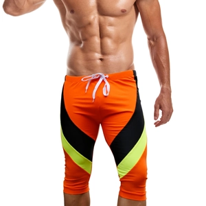 Detail of men's knee-length orange swimming trunks with contrast neon green V-shape design