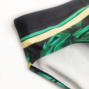 Close-up of tropical green leaf print and yellow stripe on elastic men's swim briefs