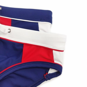 Detail of men's swim briefs featuring navy, red, and white panels with drawstring and eyelets