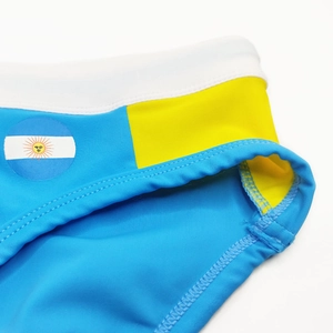 Detail of blue men's swim trunks with Argentina flag logo and yellow paneling