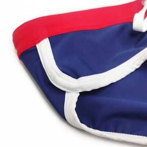 Detail view of navy blue swim briefs showing red waistband and white piping stitching