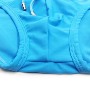 Detail of bright blue swim trunks with reinforced stitching and metal-tipped drawstring