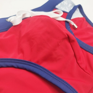 Macro detail of red men's swim trunks featuring blue piping and white drawstring