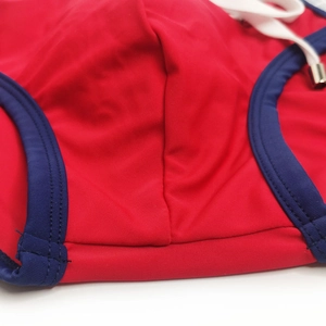 Detail view of red men's swim briefs showing blue piping, white drawstring and fine stitching