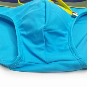 Close-up of sky blue men's swim briefs with yellow drawstring and striped waistband detail