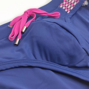 Detail of navy blue swimwear fabric featuring pink drawstrings and polka dot mesh panels