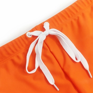 Detail of orange men's swim trunks featuring white adjustable drawstring and metal eyelets