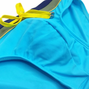 Detail of blue men swim briefs showing yellow drawstring with metallic tips and stitching
