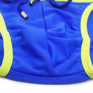 Detail of royal blue men's bikini swimwear with neon green trim and metal tipped drawstring