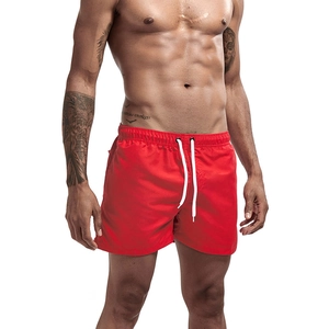 Detail of red quick-dry swim trunks featuring white adjustable drawstring and elastic waistband