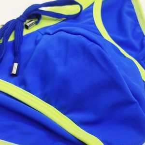Detail of royal blue bikini top with neon yellow piping and metallic drawstring tips