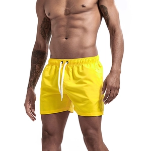 Detail of yellow quick-dry beach shorts featuring elastic waistband and white drawstring