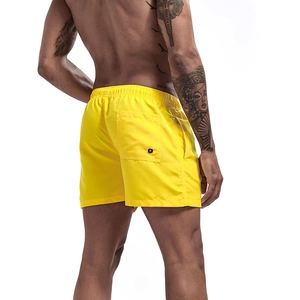 Detail of yellow quick-dry beach shorts featuring elastic waistband and back pocket with drain hole