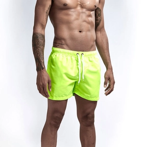 Detail of neon green quick-dry beach shorts with elastic waistband and white drawstring