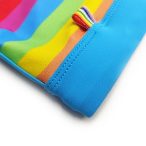 Detailed close-up of rainbow striped quick-dry swimwear fabric with blue trim and stitching