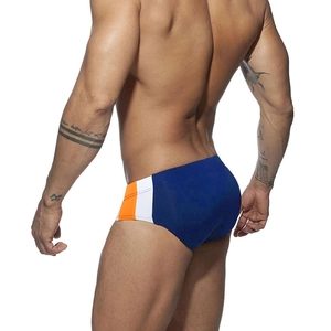 Detail view of royal blue low-rise swim briefs with white and orange side stripes