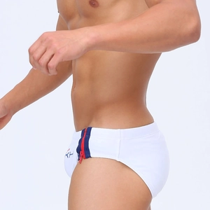 Close-up of white swim briefs featuring side red and blue zippers and logo details