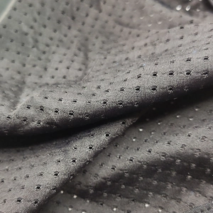 Close-up of black breathable mesh fabric with regular ventilation holes for men's swimwear