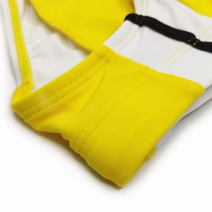 Macro detail of men's swimming briefs showing yellow and white stitching with black piping