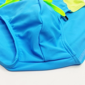 Close-up of sky blue swim briefs featuring neon contrast side panels and metal-tipped drawstring