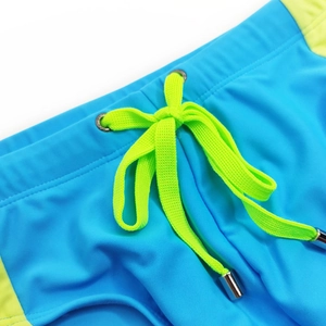 Detail of blue and lime green swim trunks showing metal eyelets and drawstring tips