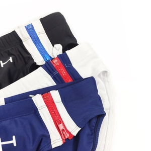 Close-up of men's quick-dry swim briefs featuring decorative side zippers and H logo