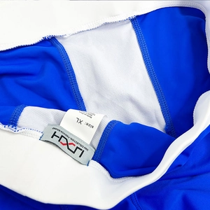 Detail view of bright blue swim shorts featuring white mesh lining and elastic waistband