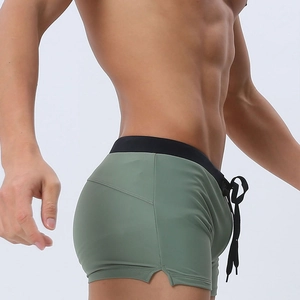 Detail shot of men's olive green swim trunks showing side slit and black drawstring waist