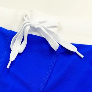 Detailed macro view of men's swim shorts with adjustable white drawstring and blue trim