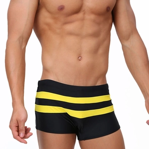Detail of men's quick-dry black swim trunks featuring three bright yellow stripes