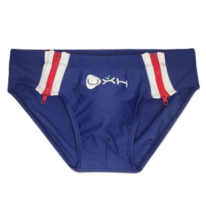 Detail view of navy blue swim briefs featuring side red zippers and white UXH brand logo