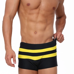 Detail of men's quick-dry black swim trunks featuring triple yellow side stripes on fabric