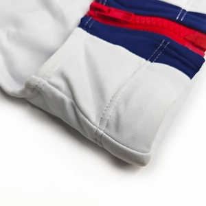 Détail de la fermeture éclair latérale avec coutures rouges et bleues sur maillot blanc