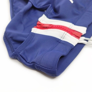 Detail view of side red zipper and red-white contrast panels on navy swim briefs