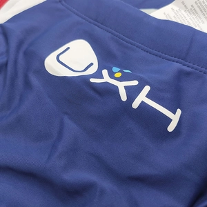 Close-up of white UXH logo and care label on blue quick-dry stretch swimwear fabric