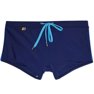 Detail of navy swim trunks featuring blue side stripes and a colorful rainbow flag tag