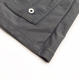 Detailed macro view of quick-dry dark grey swim trunks featuring a side drainage eyelet