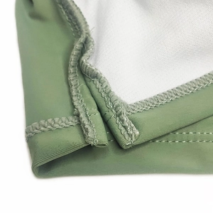 Macro shot of green swimwear fabric with white lining and reinforced double stitching