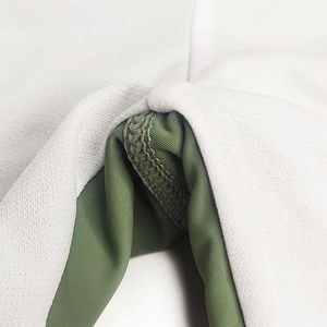 Macro shot of white textured fabric stitching with green elastic lining on men's swimwear