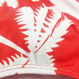 Macro view of red palm leaf print swimwear with high-quality flat-lock stitching detail