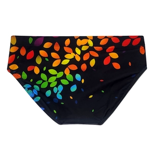 Detailed close-up of men's swim briefs featuring vibrant rainbow leaf prints on black fabric