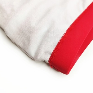 Detail of white honeycomb breathable fabric with red elastic hem and flatlock stitching
