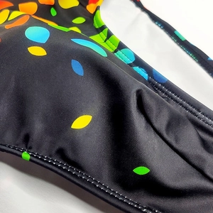 Macro shot of colorful leaf pattern and durable double-stitch on black swim trunks