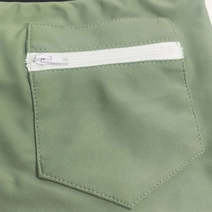 Detail of olive green swimming trunks showing back pocket with white zipper and stitching