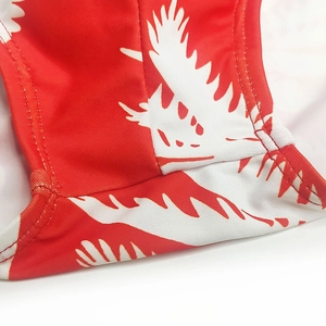 Macro detail of red swimwear fabric with white abstract print and reinforced double stitching