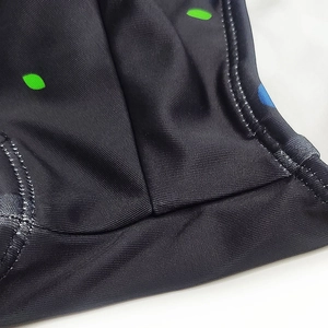 Close-up of flatlock seam stitching on black swim trunks with green and blue dots