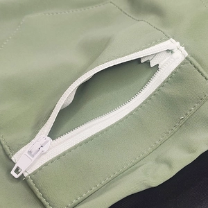 Detail of light green swim trunks featuring a white front horizontal zipper pocket