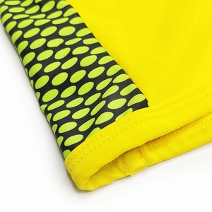 Detail view of yellow swim trunks with green polka dot side panels and double stitching